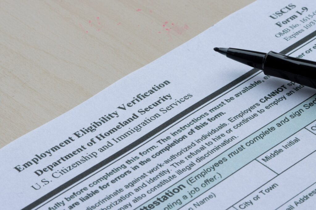Closeup of US Form I-9 with a pen resting on top.